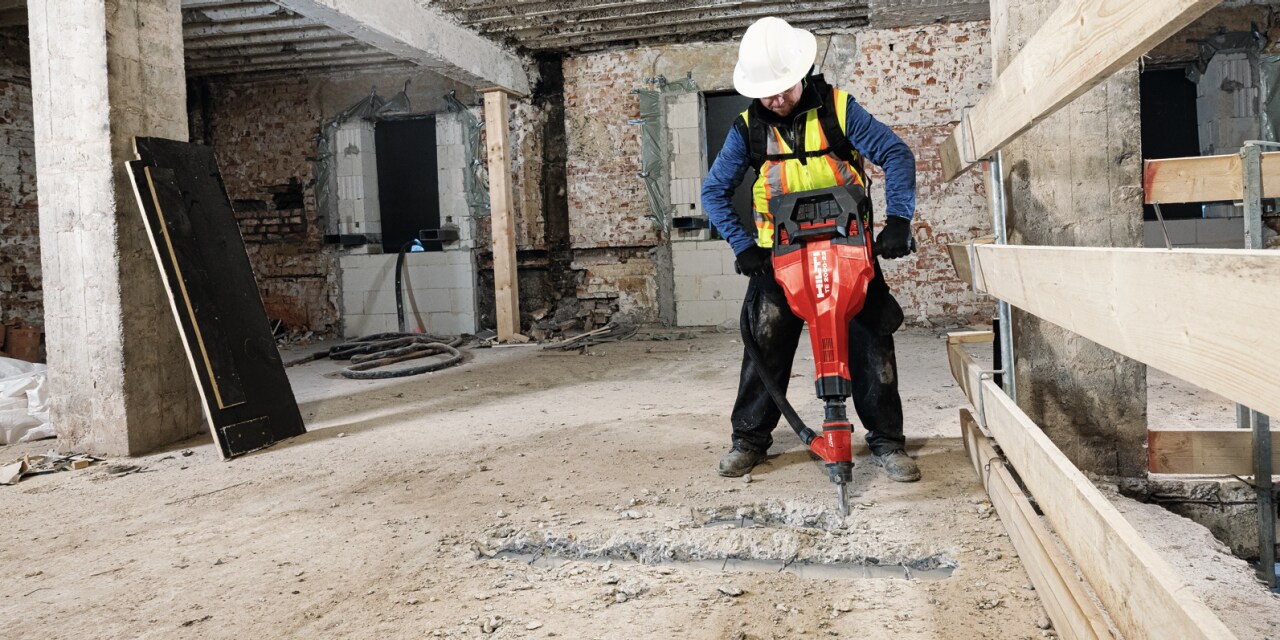 Hilti battery on cordless tool, gloved hand moves the tool's dial