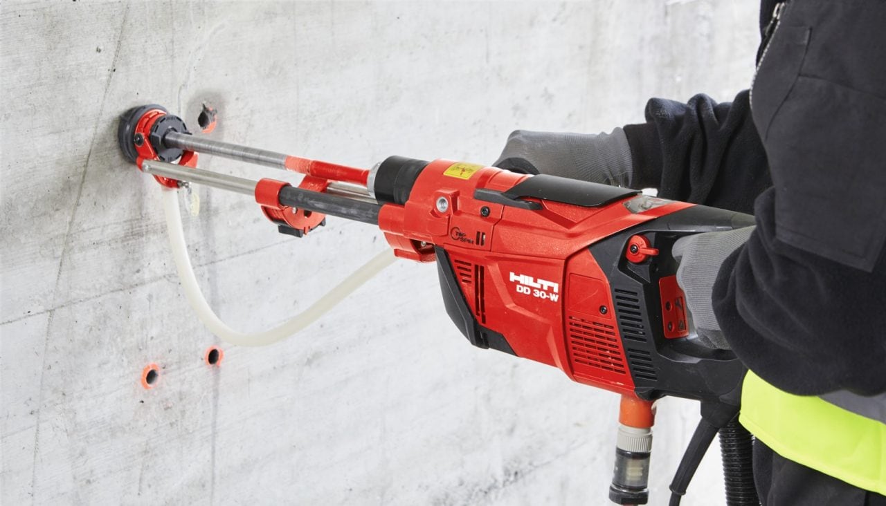 Worker performing diamond drilling in concrete wall